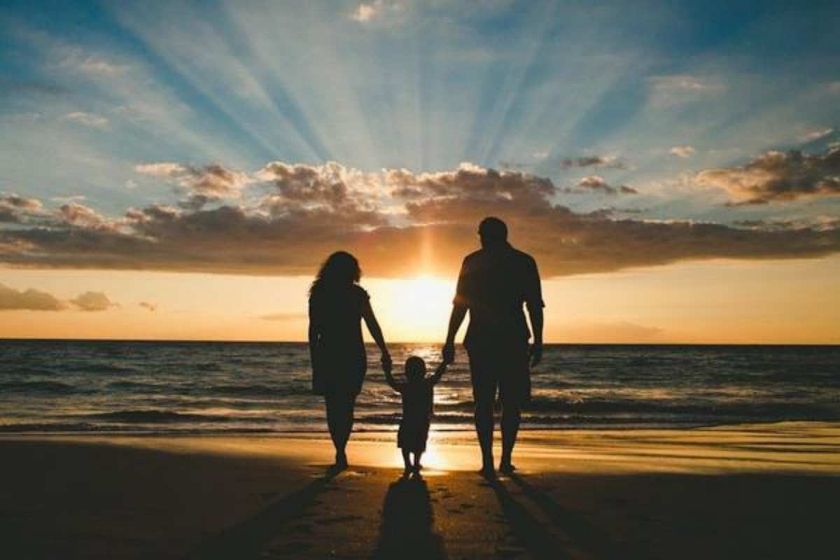 Открытка Мама и папа держат ребенка за руки. Закат на море, морской пляж  Море, пляж, закат, семья  С днем семьи 